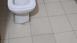 A white toilet in a bathroom with a wooden panel wall and tiled floor. - HOTEL K K PALACE (Khatoo)