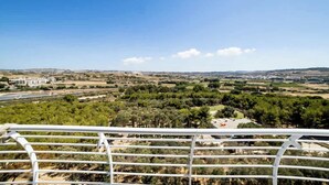 Vista panorámica desde un balcón que domina un paisaje con árboles, edificios y cielo despejado.