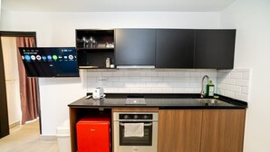 Una cocina moderna con horno integrado, un mini refrigerador rojo y una encimera negra.