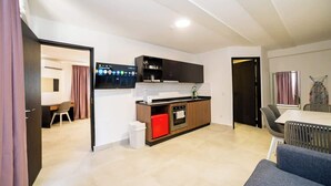 Una cocina moderna con horno integrado, un refrigerador rojo y un televisor de pantalla plana sobre la encimera.