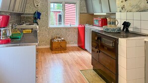 Une cuisine avec un plancher en bois, un réfrigérateur rouge, un four à micro-ondes et une cuisinière.