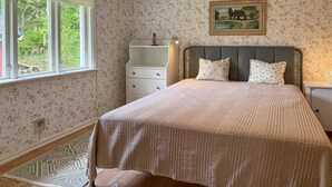 Une chambre à coucher avec un lit, une table de chevet, une commode et une fenêtre.