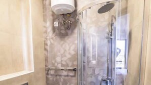 Uma casa de banho moderna com cabine de duche em vidro, sanita com função bidé e aquecedor fixado na parede.