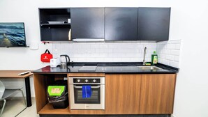 A compact kitchen with a built-in oven, a sink, and a coffee maker. - Modern Studio with Double Bed & Kitchen by HostMT (San Pawl il-Baħar)