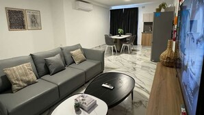 Un salon moderne avec un canapé gris, une table basse et un téléviseur posé sur un meuble en bois.