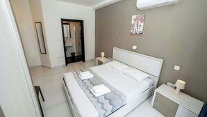 Habitación de hotel moderna con una cama grande, mesitas de noche, un espejo y un aire acondicionado de pared.