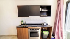 Eine moderne Küche mit Einbauofen, Mülleimer und einem schwarzen Schrank über der Arbeitsplatte.