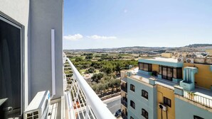Ein Balkon mit Blick auf eine Stadtlandschaft und sanfte Hügel in der Ferne.