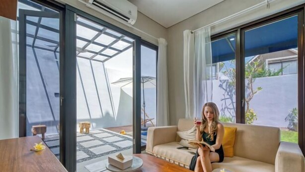 A modern living room with a sofa, coffee table, and a dining table. - Residence at Damara Village Jimbaran (Bali)