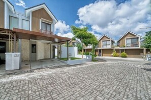 A residential area with modern houses, paved courtyard, and a clear sky.