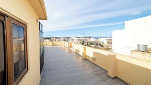 En balkon med udsigt over bybilledet og et vandområde i det fjerne.