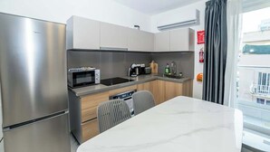 Une cuisine moderne équipée d’un réfrigérateur, d’un four à micro-ondes et d’un évier en acier inoxydable. On y trouve une table à manger avec deux chaises et une fenêtre donnant sur l’extérieur.