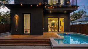A modern house with a swimming pool, wooden deck, and string lights. - Modern East Austin Stay near Rainey St, Dining & Lady Bird Lake | The Ashlee (Austin)