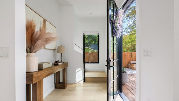 A modern interior with a wooden console table, a vase with pampas grass, and a view of the outdoors through a glass door. - Modern East Austin Stay near Rainey St, Dining & Lady Bird Lake | The Ashlee (Austin)