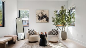 A modern living room with a large mirror, two armchairs, a coffee table, and a large abstract painting. - Modern East Austin Stay near Rainey St, Dining & Lady Bird Lake | The Ashlee (Austin)
