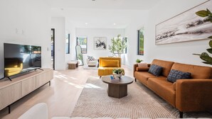 A modern living room with a TV, sofa, coffee table, and artwork. - Modern East Austin Stay near Rainey St, Dining & Lady Bird Lake | The Ashlee (Austin)