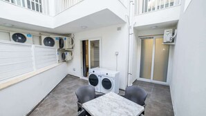 A compact, modern outdoor area with a marble table and two chairs, a washing machine, and a clothes drying unit. - Luxury 3-Bedroom Family Maisonette – by HostMT (San Pawl il-Baħar)
