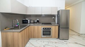 A compact kitchen with a sink, microwave, toaster, coffee maker, oven, and refrigerator. - Luxury 3-Bedroom Family Maisonette – by HostMT (San Pawl il-Baħar)