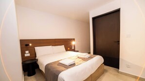 A modern hotel room with a large bed, a bedside table, and a wardrobe. - Bright Penthouse with Private Terrace by HostMT (San Pawl il-Baħar)