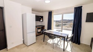 A compact kitchen with a refrigerator, oven, and a dining table with chairs. - Bright Penthouse with Private Terrace by HostMT (San Pawl il-Baħar)
