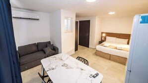 A compact hotel room with a bed, a small table, a sofa, and a dining area. - Bright Penthouse with Private Terrace by HostMT (San Pawl il-Baħar)