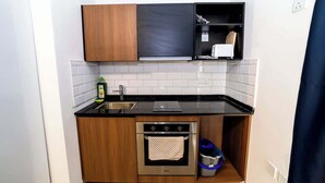 A compact kitchen with wooden cabinets, a stainless steel oven, a sink, and a microwave. - Bright Penthouse with Private Terrace by HostMT (San Pawl il-Baħar)
