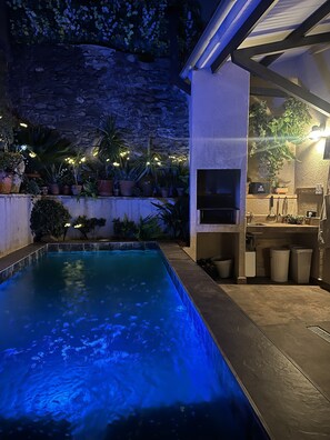 A swimming pool with blue lighting, surrounded by potted plants and a stone wall. - Rural House La Real de Guadalupe (Guadalupe)