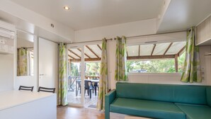 A room with a sofa, a table, chairs, and a sliding glass door leading to an outdoor area.