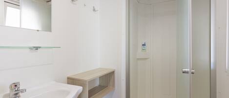 A bathroom with a white sink, mirror, and glass shower enclosure.