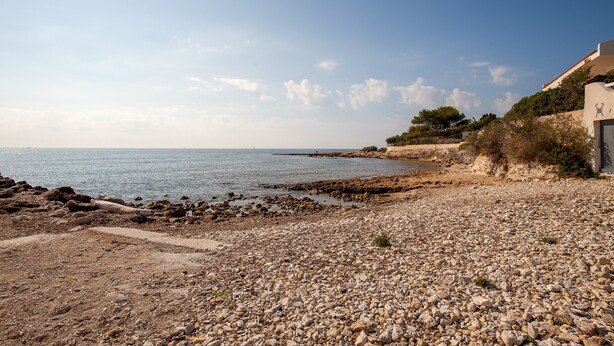 A rocky beach with a building on the right.