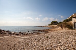 Ein felsiger Strandabschnitt, rechts ein Gebäude.