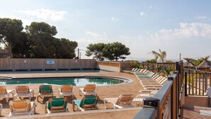A pool area with lounge chairs and a wooden fence.