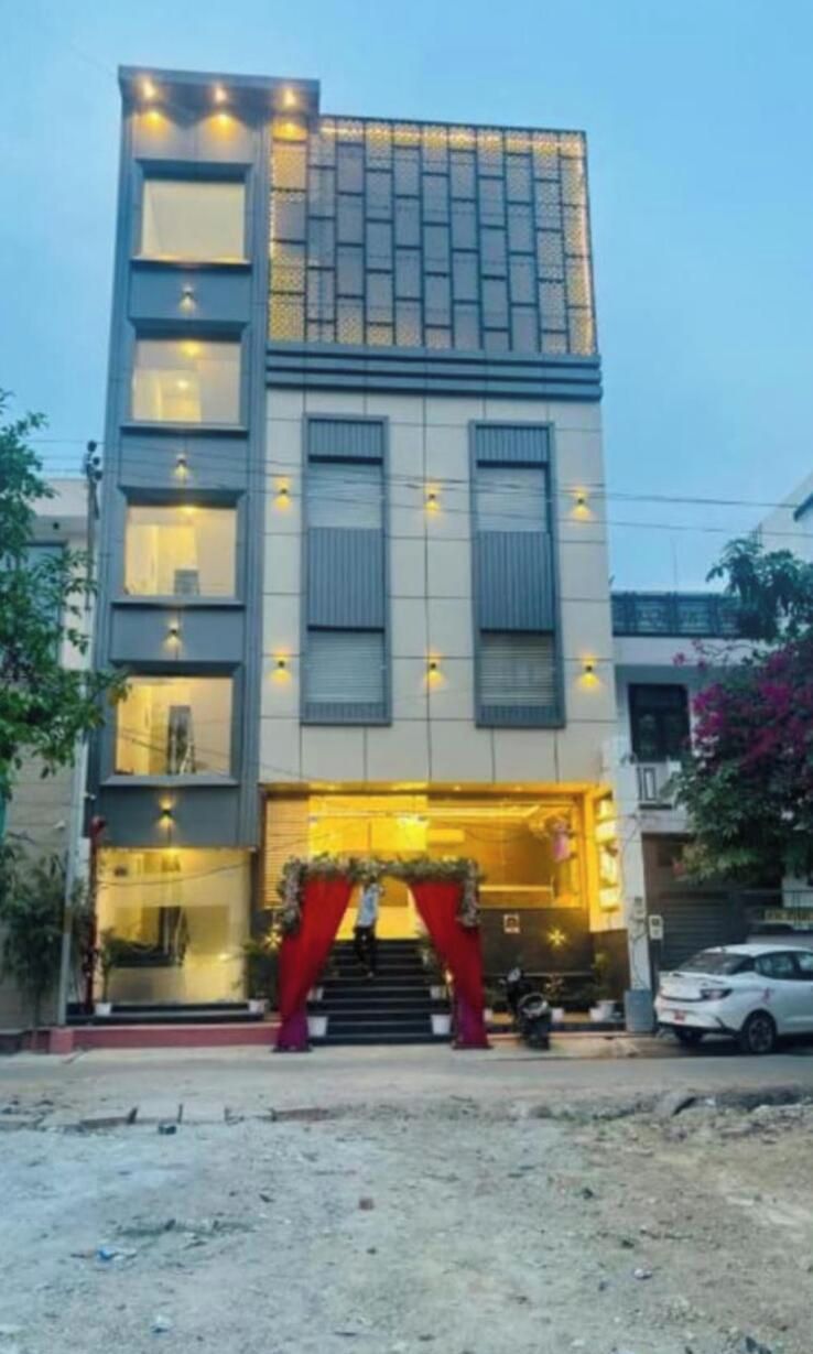 Un edificio de varios pisos con un diseño moderno, que presenta una entrada destacada con un arco rojo y una escalera que lleva a ella.