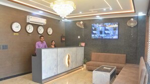 A modern reception area with a marble reception desk, a sofa, and a coffee table. - Hotel AU Villa (Etmadpur)
