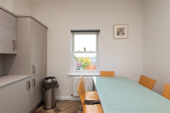 A compact kitchen with a window, a radiator, and a trash bin. - Toast Stays - The Orchard Suite (Durham)