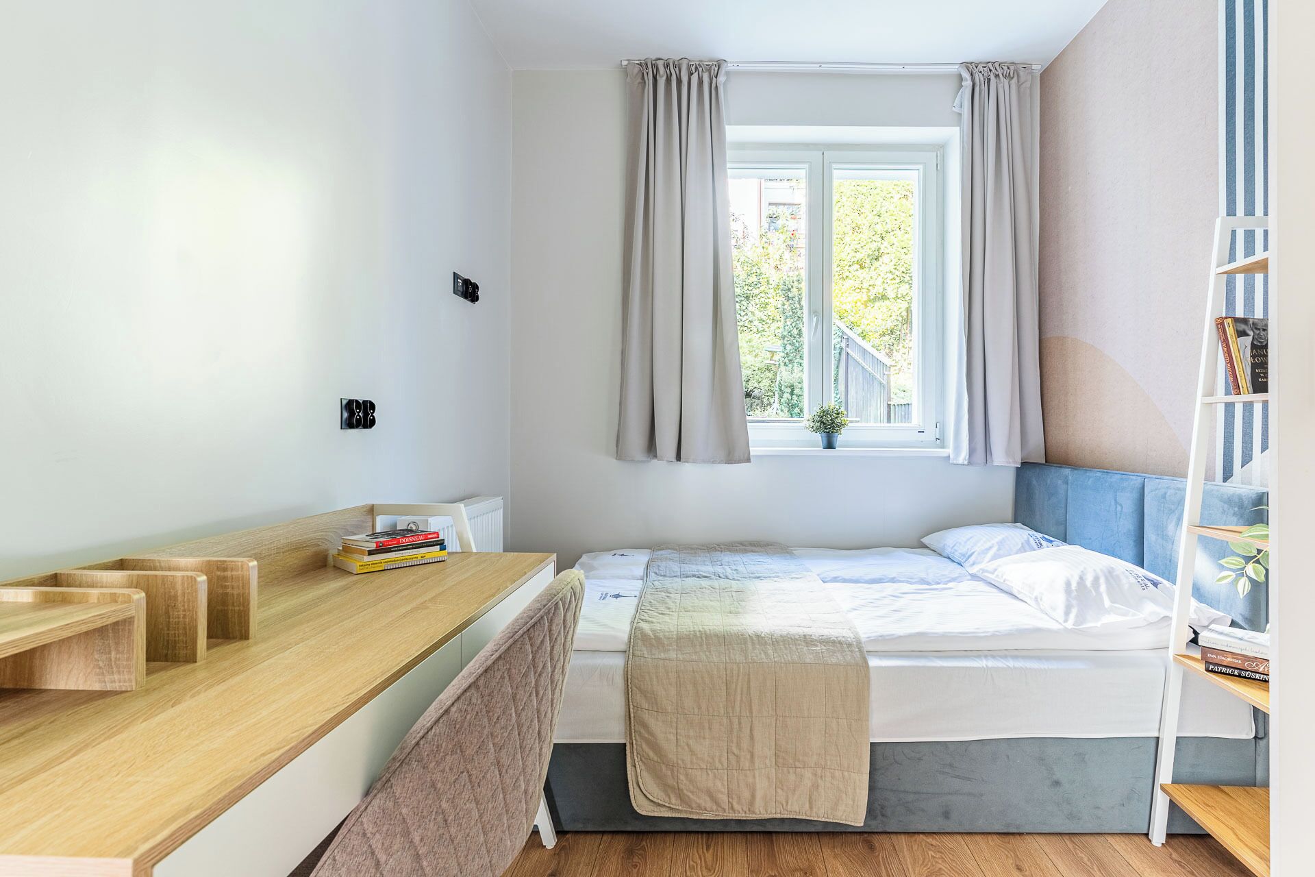 A bedroom with a bed, bedside table, and a window with curtains.