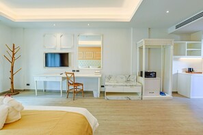 Une chambre d’hôtel comprenant un lit, un bureau avec une chaise, une télévision, un coin salon avec un banc rembourré et une petite armoire avec des tiroirs.