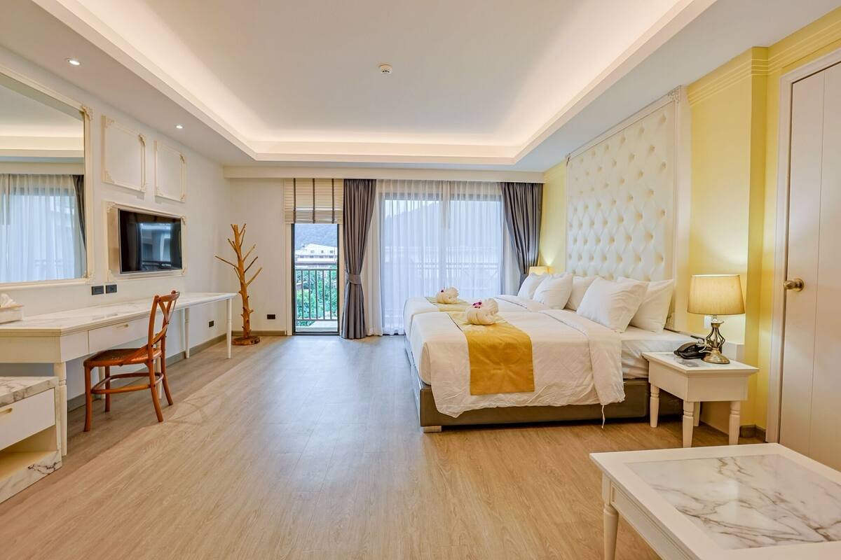 Een hotelkamer met een bed, nachtkastje, lamp, bureau, stoel en een televisie.