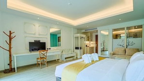 Een hotelkamer met een groot bed, een bureau met een televisie, een stoel, een bank en een spiegel.