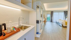 Een moderne hotelkamer met kitchenette, een groot bed en uitzicht op de omgeving.