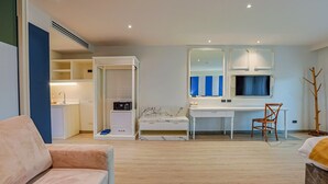 Een moderne slaapkamer met een bed, een bureau en een stoel. Er is een kledingkast, een spiegel en een televisie.