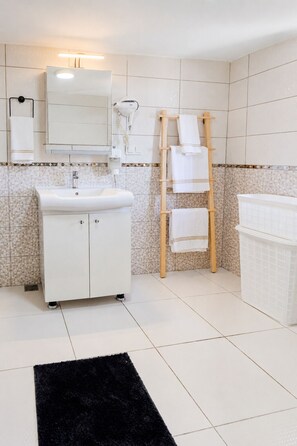 Une salle de bain avec un lavabo blanc, un miroir, un porte-serviettes et un tapis noir.