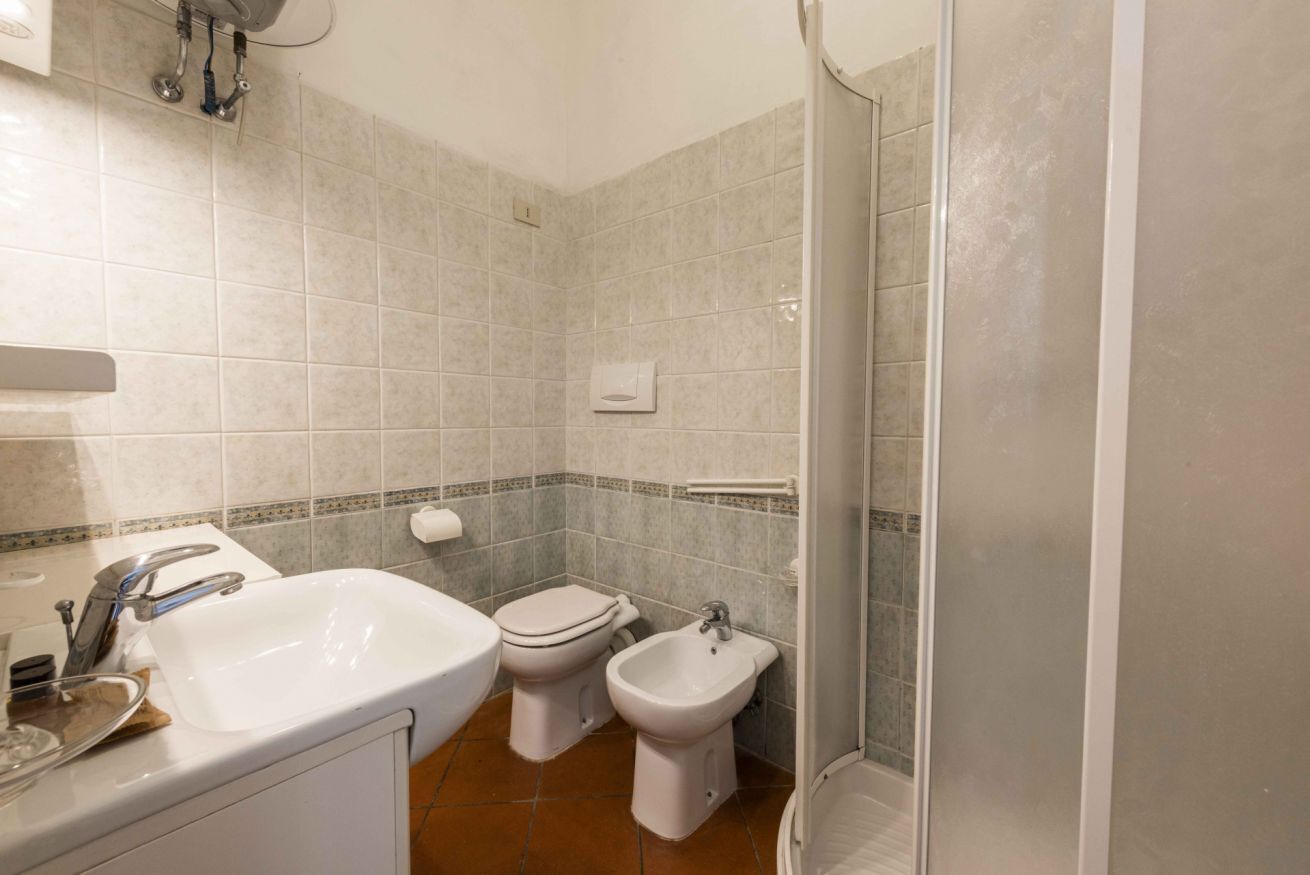A bathroom with a sink, toilet, bidet, and shower.