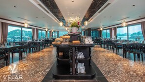 A restaurant with a central bar area, multiple dining tables, and chairs. - Dragon Premium Cruise (Tuan Chau)
