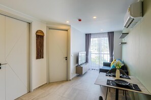A modern kitchen with a dining area, a built-in oven, and a window with curtains. - Classic Studio Apt T3-329 (Chalong)