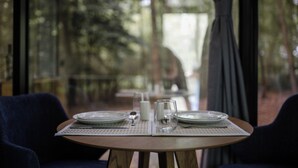 A dining table set with plates, glasses, and a milk jug, with a view of a forest through a window. - Mala Vila (Gradec)
