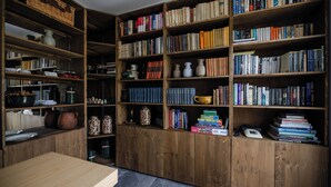 A room with a wooden bookshelf filled with books, a wooden table, and various kitchen items. - Mala Vila (Gradec)