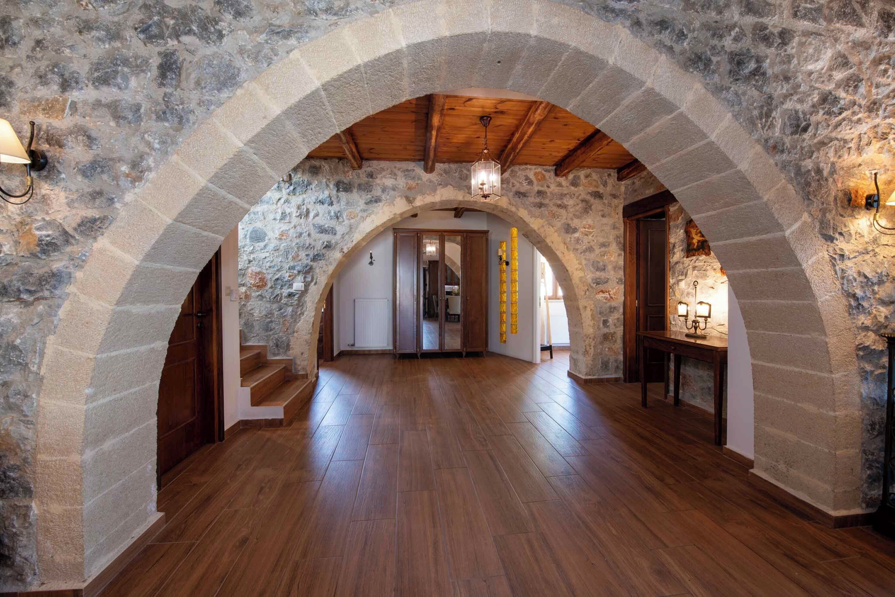 A stone-walled hallway with wooden flooring and a wooden ceiling.