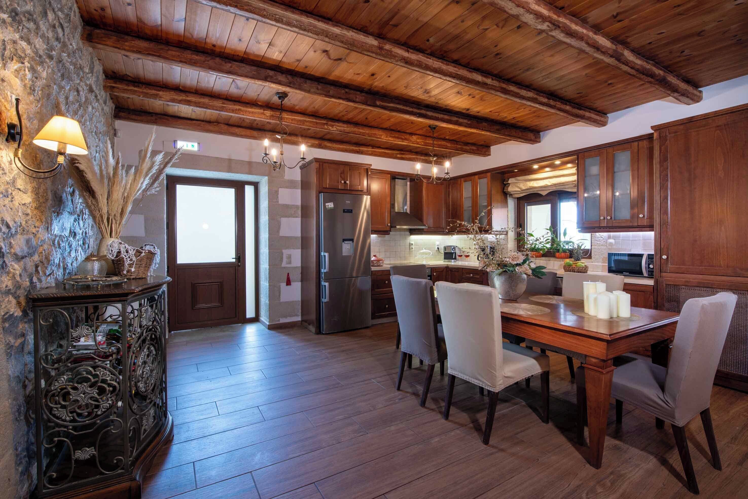 A spacious kitchen with wooden cabinets, a stainless steel refrigerator, and a dining table set for four.