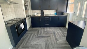 A compact kitchen with dark cabinets, a gas stove, and a herringbone-patterned floor.
